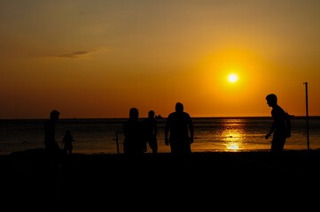 Naklejka na ściany i meble Amateurs playing football at Jumeira beach in Santa Marta, Colombia during sunset.