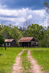 Fototapeta na wymiar Disused wooden homestead surrounded by grazing field and dramatic stormy sky in Kroombit Tops National Park, Queensland