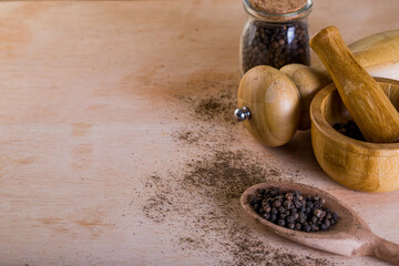 A lot of blackpeppers on wooden background.