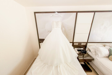 Fototapeta na wymiar Wedding gown dress hanging on holder in the room before outdoor wedding of tropical caribbean destination marriage matrimonial ceremony 