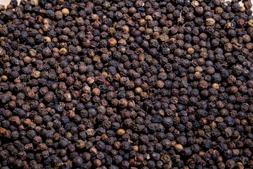 A lot of blackpeppers on wooden background.
