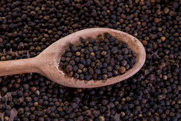 A lot of blackpeppers on wooden background.