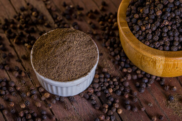 A lot of blackpeppers on wooden background.