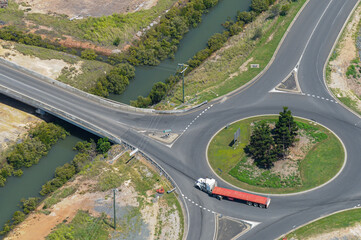 Articulated semi trailer truck going around a rounabout next to a bridge over a creek in Gladstone.