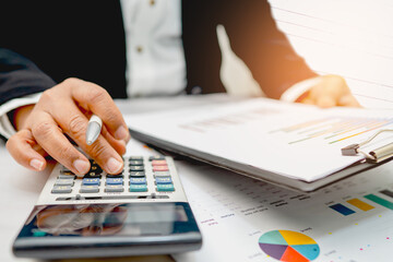 Asian accountant working and analyzing financial reports project accounting with chart graph and...