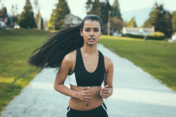 Woman of color running in the park, looking straight at the camera