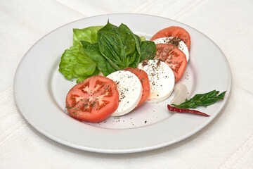 Ensalada Caprese de tomate, albahaca, mozzarella, queso fresco, espinaca y pimienta negra espolvoreada  