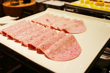 Slices of ham on a restaurant breakfast buffet.