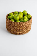 Fresh,ripe green color plums in the round,wicker basket on the white background with copy space.