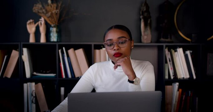 Zoom in portrait of young 20-25 year old smart beautiful African woman using laptop at home, procrastinating slow motion