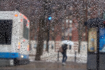 People on a bus stop on a rainy evening, blurred abstract picture with car lights