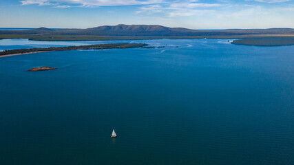 Fototapeta premium Small sailing boat in vast seascape between Bird Island and Turkey Beach, Queensland
