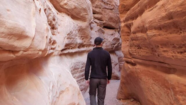 Slow motion shot of young man walking in orange rock passage in Valley of Fire State Park, Nevada, USA