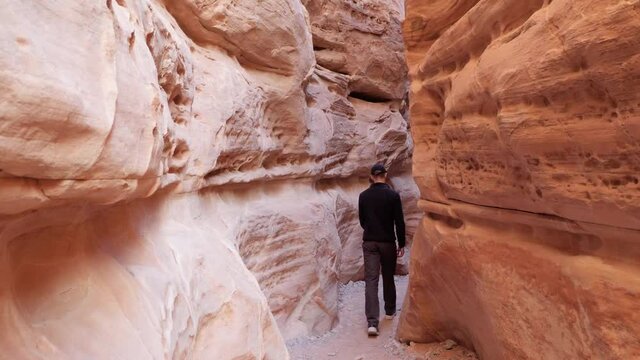 Young man walking in orange rock passage in Valley of Fire State Park, Nevada, USA