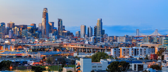 San Francisco city skyline panorama after sunset with city lights, the Bay Bridge and light trails leading into the city