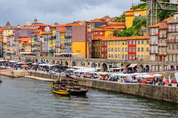 Fototapeta na wymiar Traditional Portuguese houses with Azulejo tile in the Ribeira and tourist rabelo boat docked on Douro in Porto Portugal