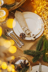 Christmas table setting. New Year's decor: fir cones and branches, cotton balls, a garland and silver cutlery.