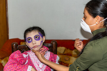 Young woman putting makeup of Catrina in a girl's face