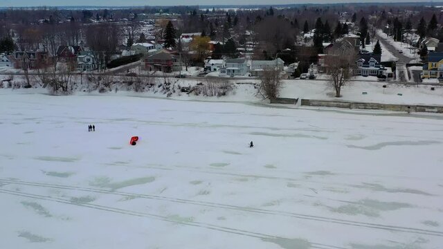 group of people walking over a frozen lake approachig a person tht was doing some kiteboarding