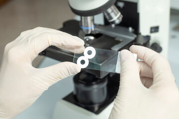 doctor's hands analyzing virus sample with microscope foreground
