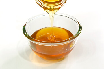 Pour Fresh honey bee in bowl on white background.