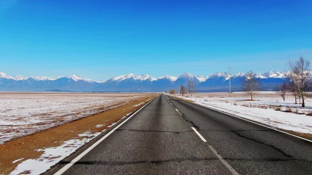 Straight line winter road trip to mountains 4K. Fast speed motion traveling down point. Beautiful blue mountain valley on winter road. Amazing landscape for trip car. Pov travel highway with hill.