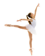 Cute little girl in a tutu and pointe shoes dancing in the studio on a white background.