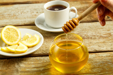 Spoon for honey with drops of honey in a female hand.