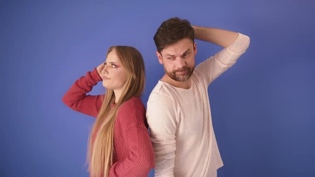 Portrait of angry offended couple man and woman standing back to back isolated over blue background. Domestic life concept