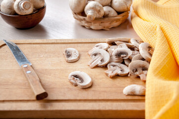Still life: basket with mushrooms, cutting Board with slices of mushrooms on the table, knife and yellow towel