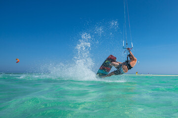 kiter does a difficult trick on a background of transparent water and blue sky