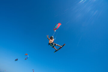 kiter does a difficult trick on a background of transparent water and blue sky