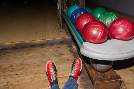 Very Old Colorful And Damaged Bowling Balls And Bowling Shoes On Man Legs Background