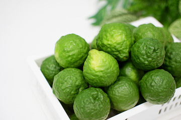 Bergamot, green fruit, stacked in a white basket