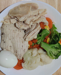 Streamed organic chicken breast serving with sliced medium boiled egg and various vegetables corn carrot peas Broccoli on white flat plate, homemade, fresh market restaurant, food menu advertising bac