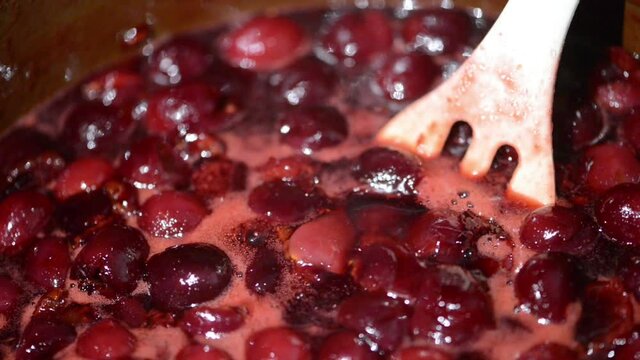 Cooking tasty cherry fruit jam in a pot. mixing the cherries.