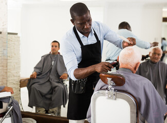 Hairdresser doing styling with hair clipper