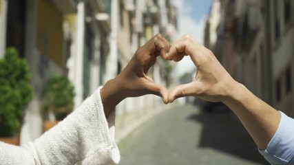 Happy mix raced dating couple standing on street outdoors, connecting hands in love gesture, forming and showing heart shape with fingers. Closeup, zoom, cropped shot. Romance and relationship concept - Powered by Adobe