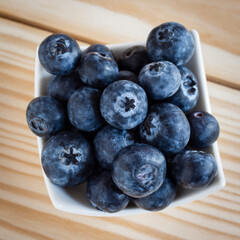 Squared top view shot of blueberries fresh fruit ingredient on a wooden background.