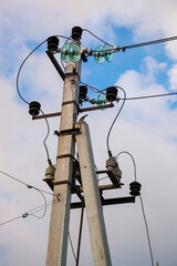 Close-up of power poles with wires on a blue sky with clouds.