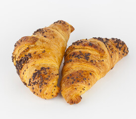 Two french croissant filled with hazelnut and covered with chocolate nuggets on white background. French pastries.