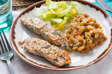 Top view food shot of a whole food diet healthy meal with cooked salmon, ratatouille and cucumber salad. Gourmet and delicious plate with high nutritious value for athletes and fitness enthusiasts.