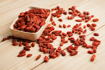 Top view shot of goji berries spreaded on wooden background. This red product comes from China,...