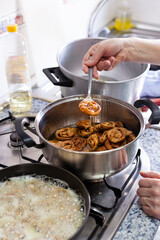 Vertical shot Moroccan Chebakia homemade traditional elaboration represented by the fried chebakia submerged on honey with a woman hand´s taking them to another container to continue dropping honey.