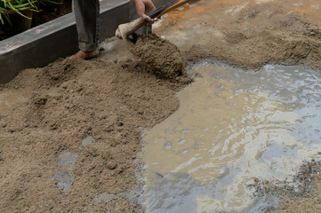 Indian labour mixing cement and water manually on floor using a shovel. Stock image.