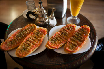 Mediterranean breakfast and healthy couple lifestyle concept shot with delicious tomato and spices toasted bread, tea, teapot, salt shaker, napkins and orange juice. Granada gastronomy stills.