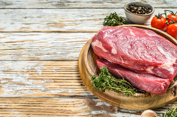 Raw Round beef cut on a wooden board. White background. Top view. Copy space