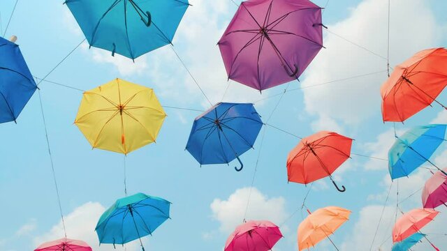 Colorful umbrellas hanging in the sky, lane decorated colored umbrellas. vivid colorful umbrellas sweep overhead against the blue sky