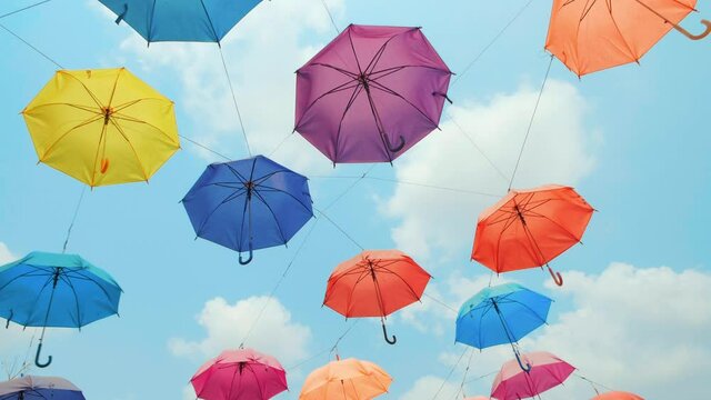 Colorful umbrellas hanging in the sky, lane decorated colored umbrellas. vivid colorful umbrellas sweep overhead against the blue sky