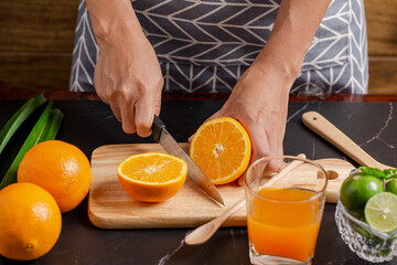 Closeup on women cutting orange for make juice on kitchen table.